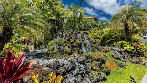 A tropical garden with a waterfall, lush greenery, and a clear blue sky. - Grand Champions #86 Gorgeous Views On Golf Course, Near Popular Beaches (Wailea)