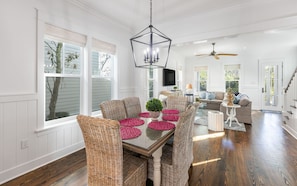 A spacious dining area with a glass-top table, wicker chairs, and pink placemats.