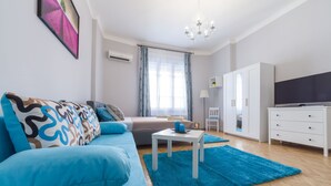 A modern living room with a blue sofa, a small white table, and a blue rug. - Real Apartments Wesselényi III.  (Budapest)