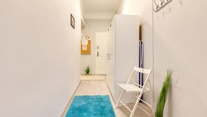 A hallway with a blue rug, a white chair, and a plant. - Real Apartments Wesselényi III.  (Budapest)