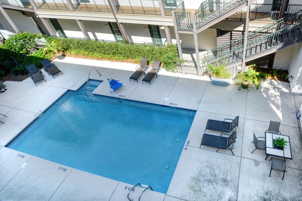 A rooftop pool with lounge chairs and a table, surrounded by a building with multiple balconies. - Pet Friendly, Updated 1 Bedroom Getaway at Ocean Suites (Saint Simons Island)