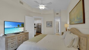 A bedroom with a bed, a television on a dresser, a ceiling fan, and a painting on the wall. - Pet Friendly, Updated 1 Bedroom Getaway at Ocean Suites (Saint Simons Island)