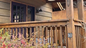 Ein Holzhaus mit Veranda, einem Schild mit der Nummer 90 und einer Glocke.