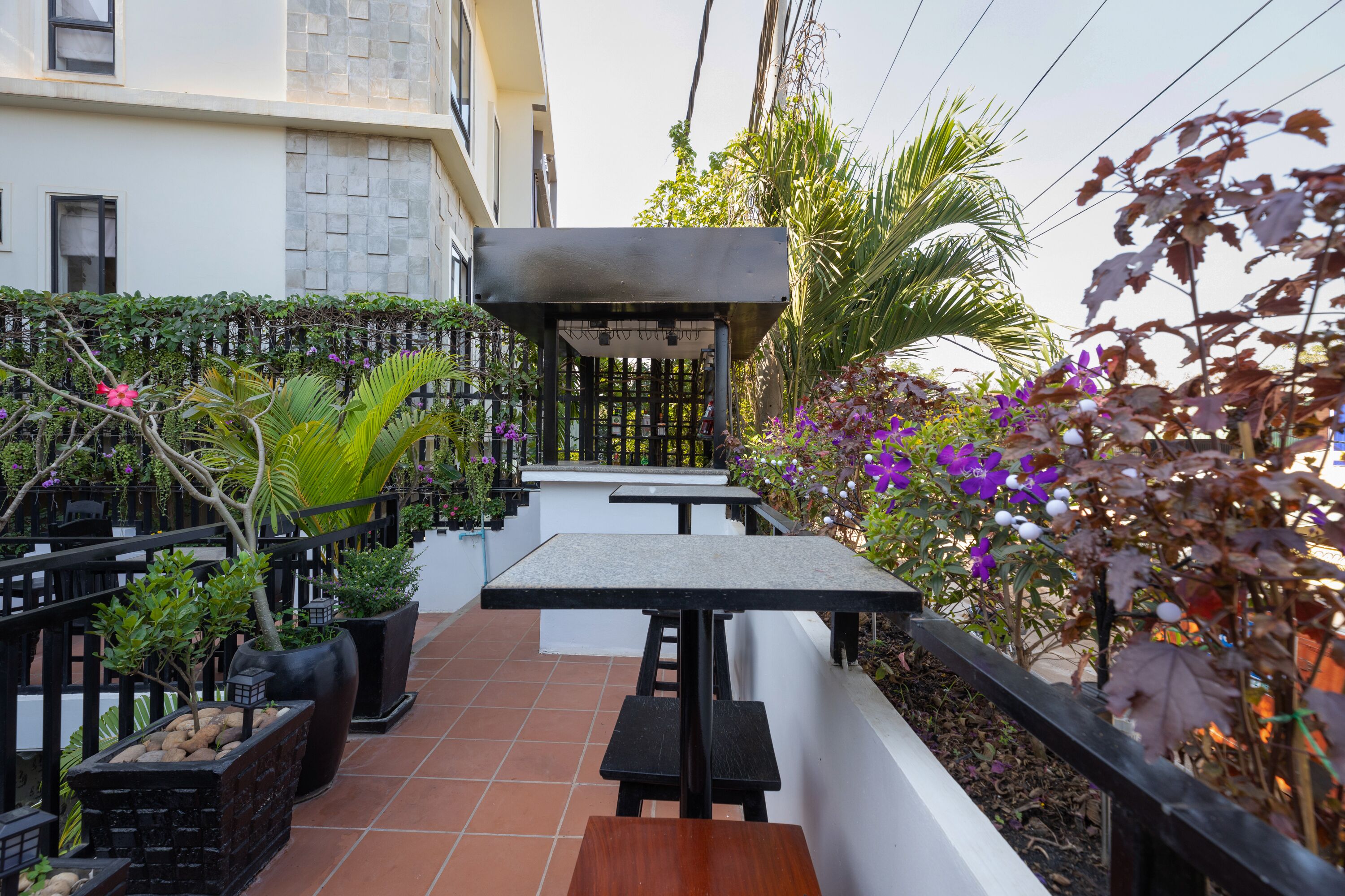Un patio con mobiliario exterior, una pérgola y diversas plantas y flores.