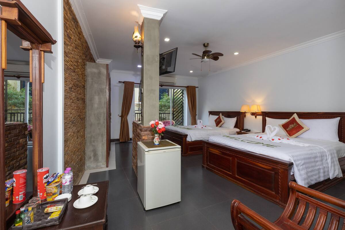 A hotel room with a bed, a desk, a refrigerator, and a TV.