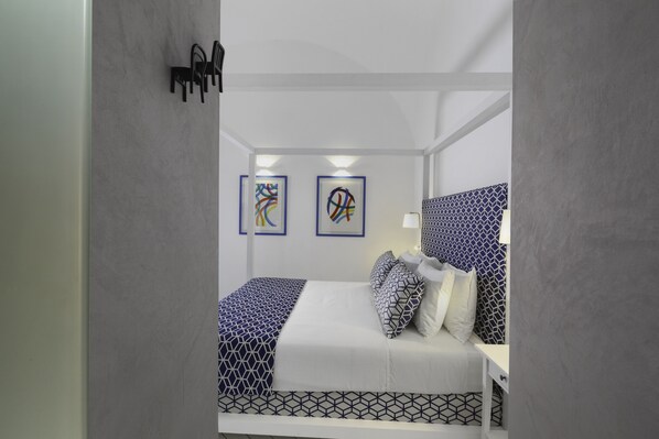 A modern bedroom with a bed, bedside table, and two abstract art pieces on the wall. - Iommella luxury rooms (Sant'Agnello)