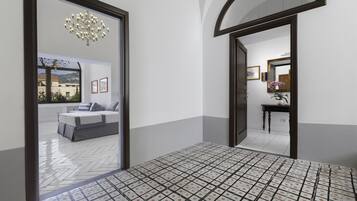 A hotel lobby with a tiled floor, a bed in the background, and a chandelier.