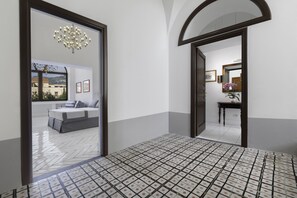 A hotel lobby with a tiled floor, a bed in the background, and a chandelier. - Iommella luxury rooms (Sant'Agnello)