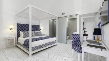 A modern bedroom with a four-poster bed, a desk with a laptop, and a bathroom with a shower and toilet.