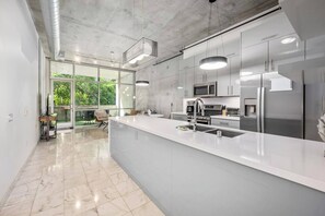 A modern kitchen with a large island, stainless steel appliances, and a view to the outdoors.