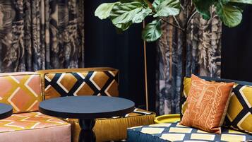 Una sala de estar moderna con un sofá, reposapiés y una planta grande.