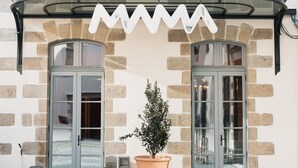 Ein Gebäude mit einer Steinfassade, zwei großen Glastüren und einem Blumentopf davor.