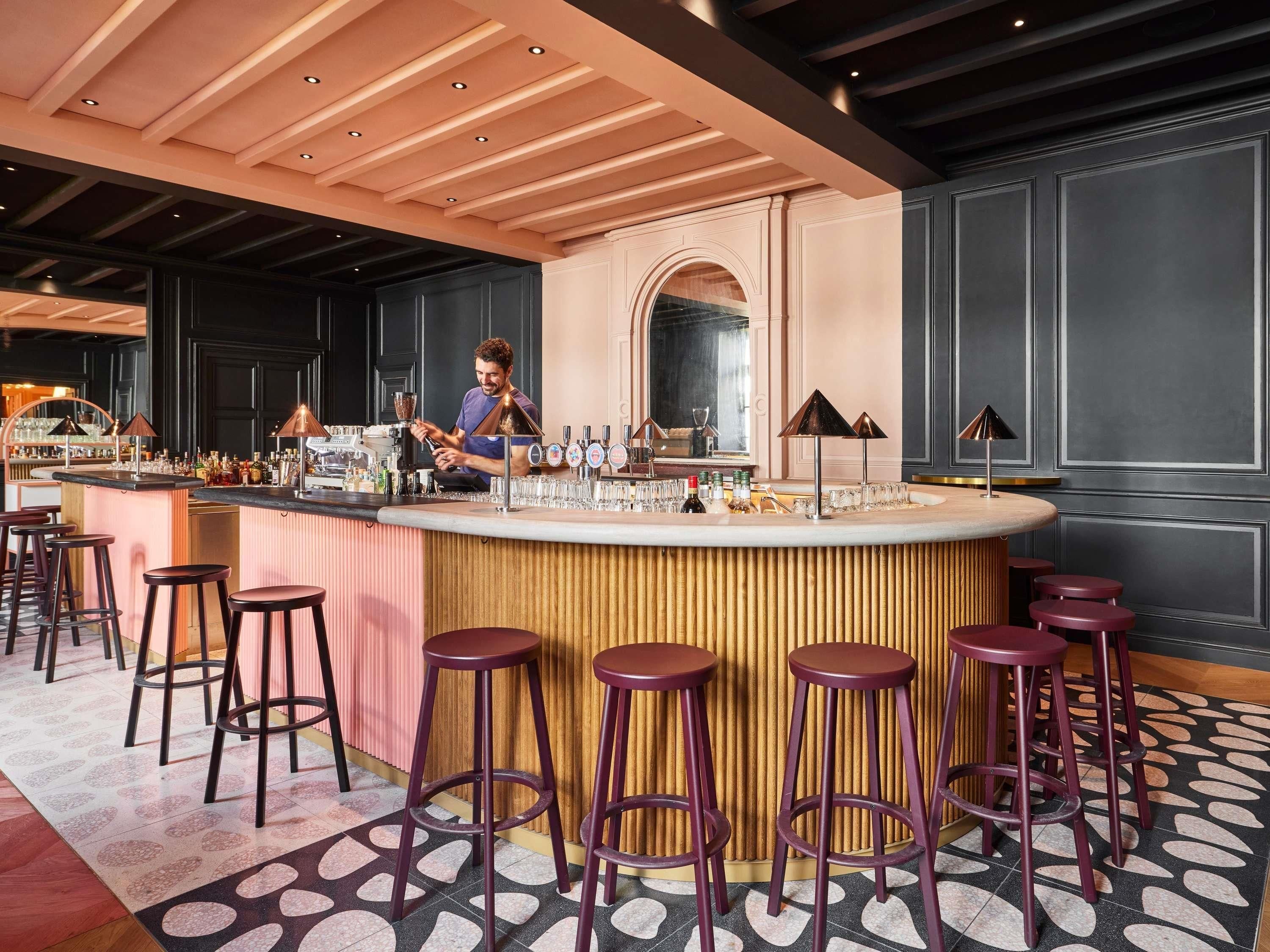 Zona de bar con un bartender, taburetes y una barra.