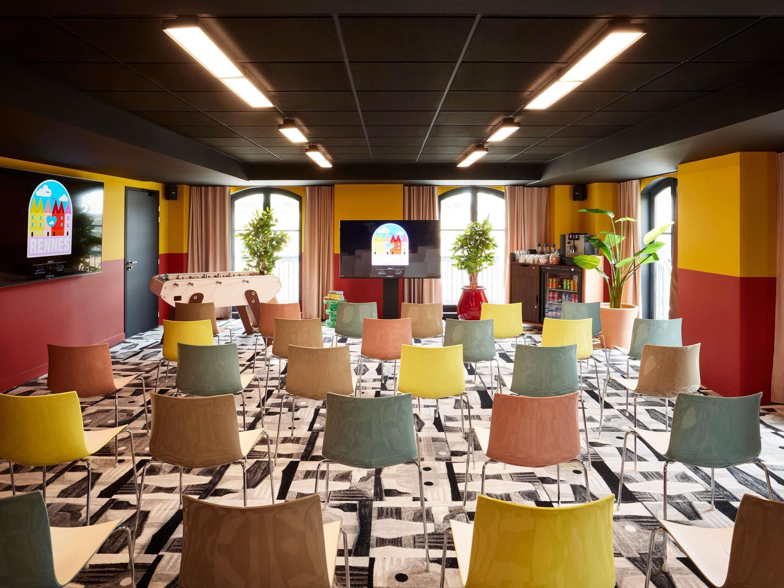Une salle de conférence équipée de plusieurs chaises, d’un téléviseur et de plantes en pot.