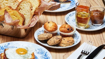 Un desayuno con pan, muffins y té sobre una mesa de madera.
