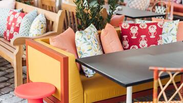 Un espace extérieur aménagé avec des meubles en bois, des coussins jaunes et des oreillers à motifs rouges et blancs.