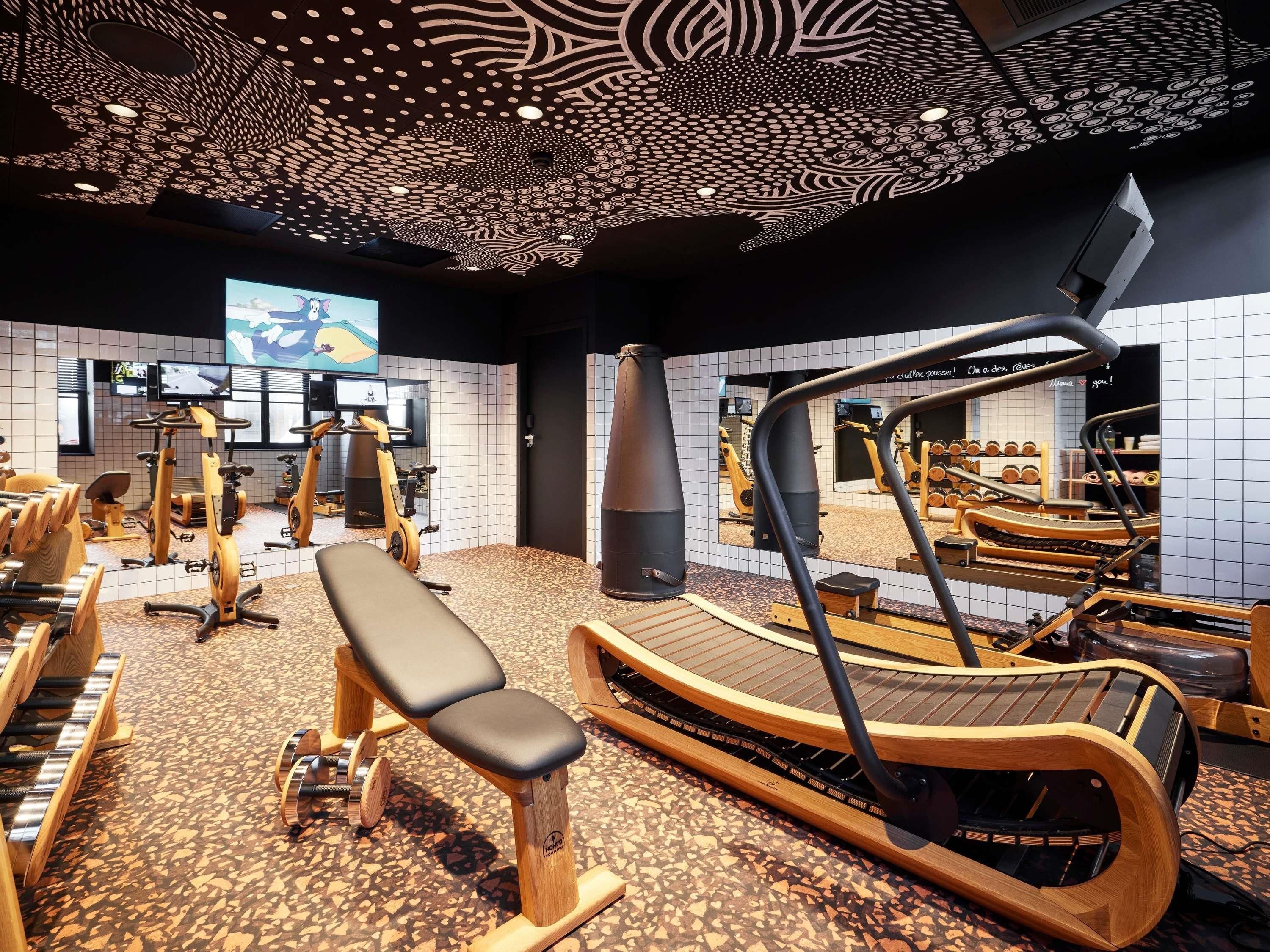 Een sportschool met trainingsapparatuur, een grote spiegel en een behangplafon.