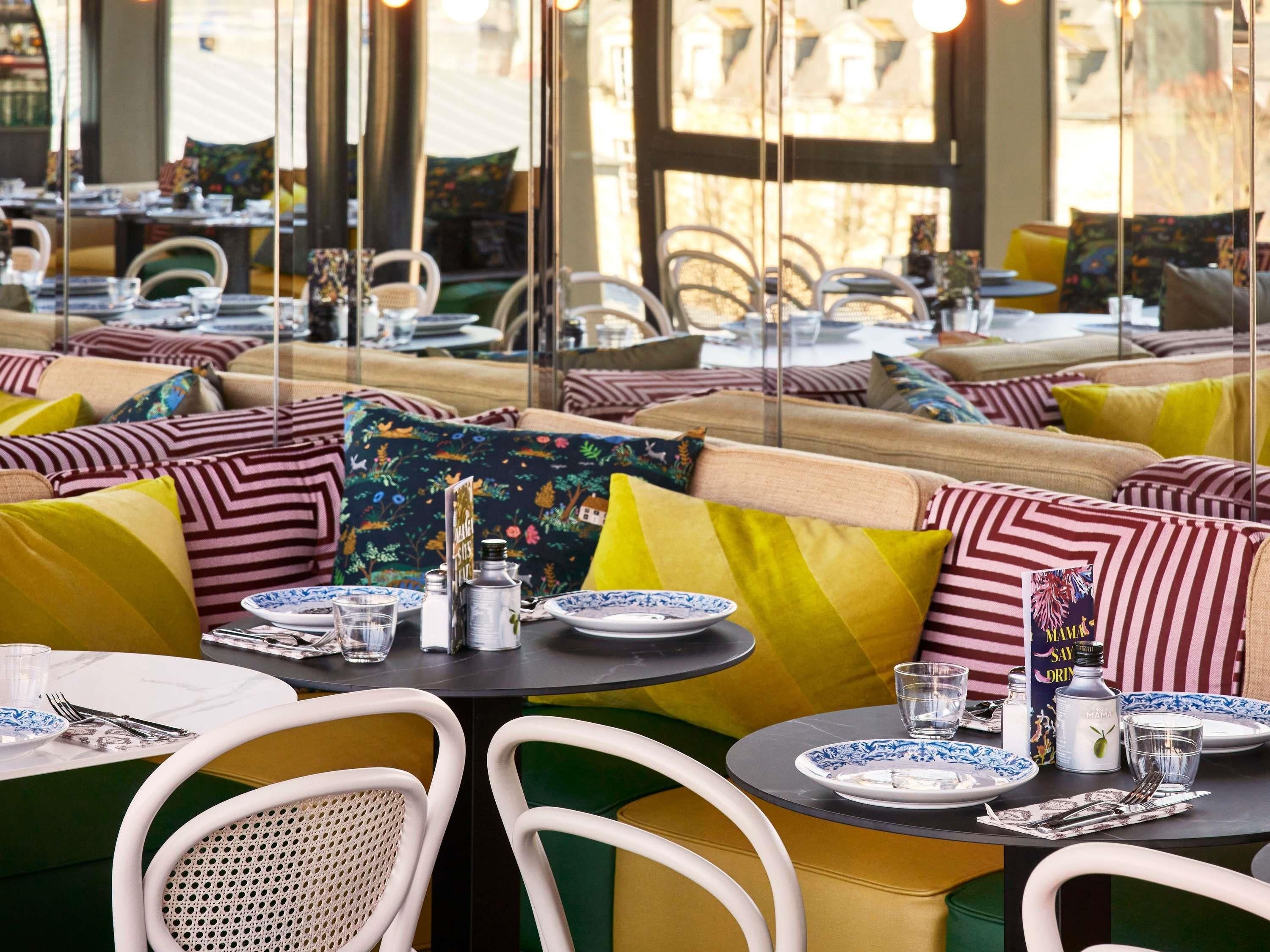 Un restaurant avec des tables rondes, des sièges confortables et une vue dégagée grâce à de grandes fenêtres.