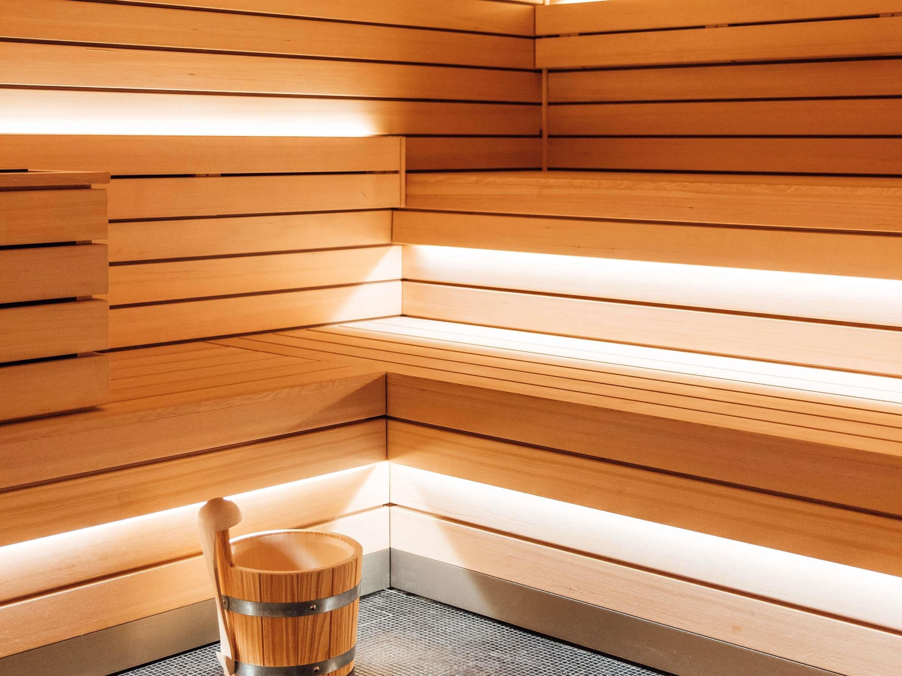 Un sauna avec des parois en lattes de bois et un seau en bois.