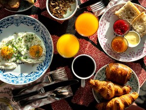 A breakfast setting with eggs, toast, croissants, and beverages on a patterned tablecloth. - Mama Shelter Rennes (Rennes)