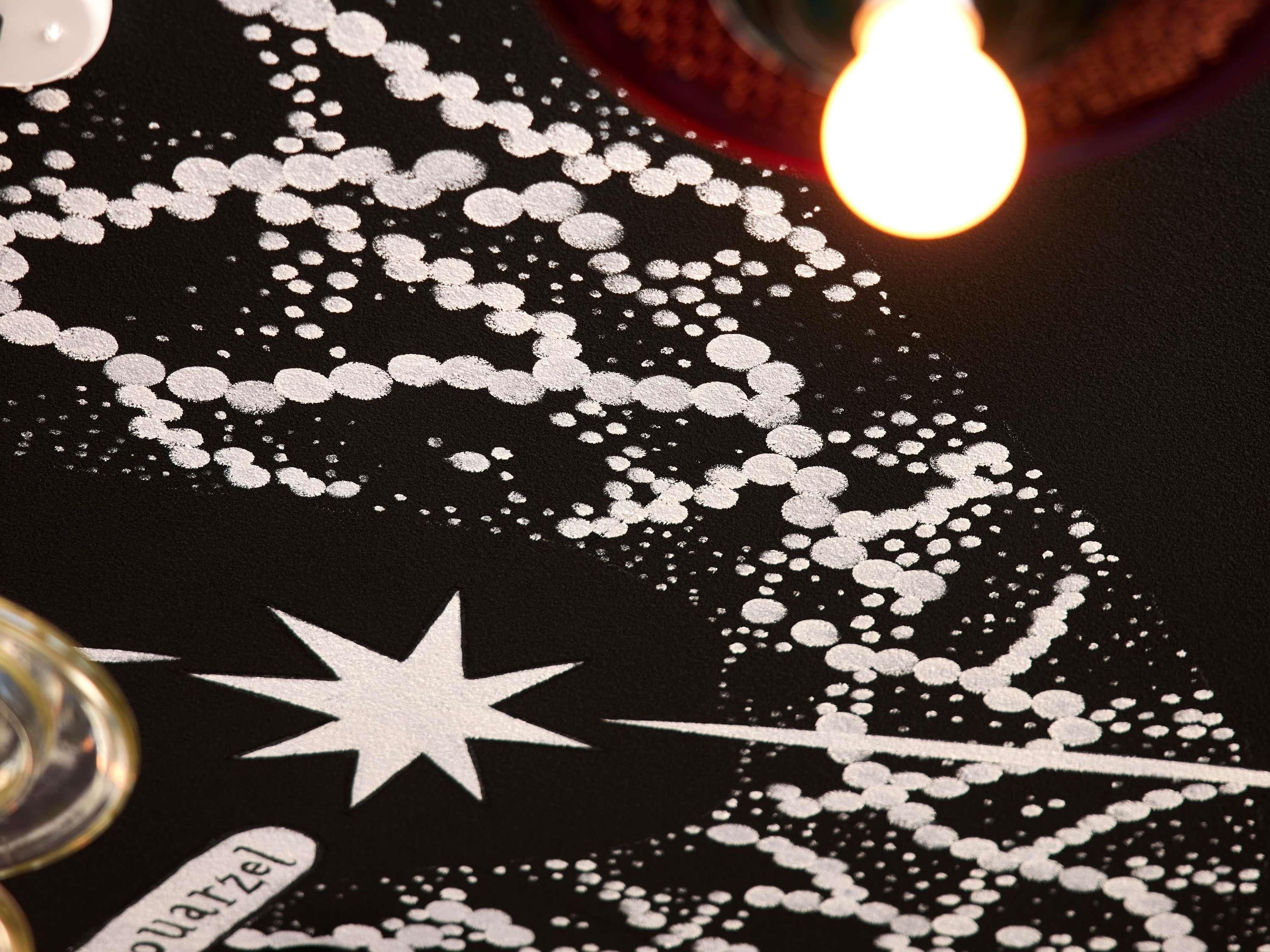 A close-up of a black surface with white decorative patterns, including a star and the word 'QUARTZEL'.