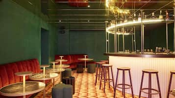 Zona de bar con una barra curva, taburetes y un banco tapizado de rojo.