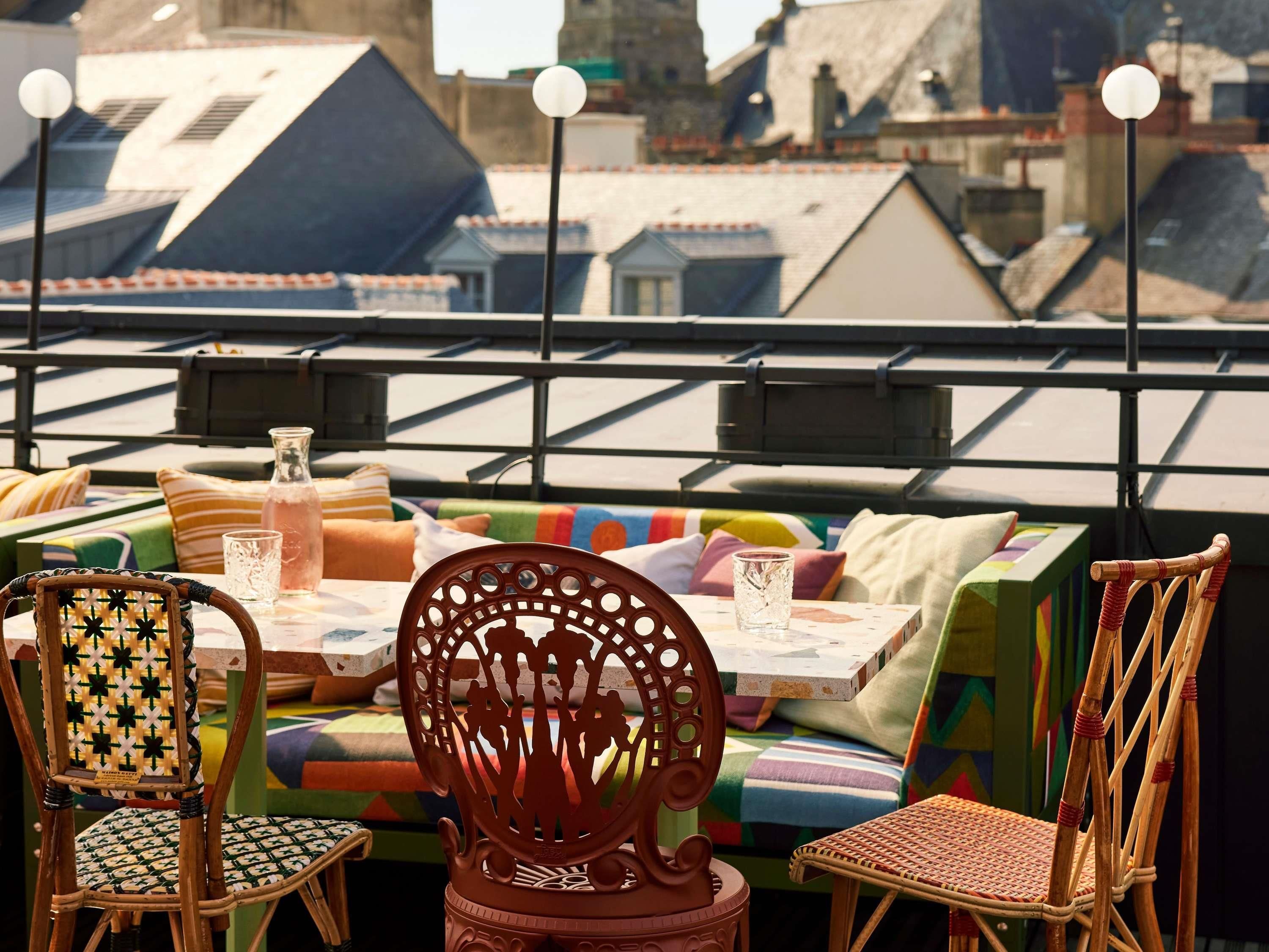 A rooftop terrace with a table, chairs, and colorful cushions.
