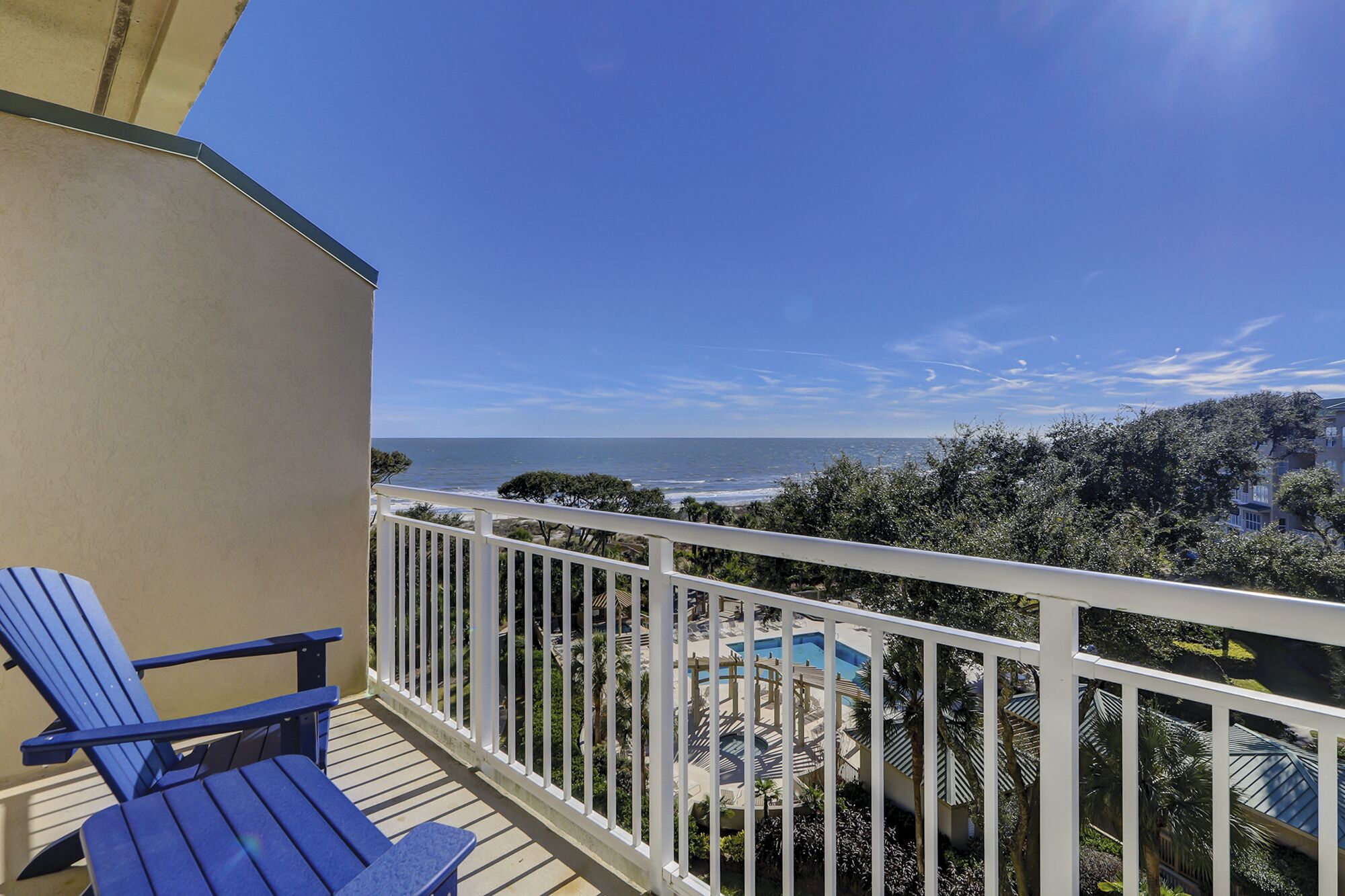 Ein Balkon mit Blick auf den Ozean und einen Poolbereich.