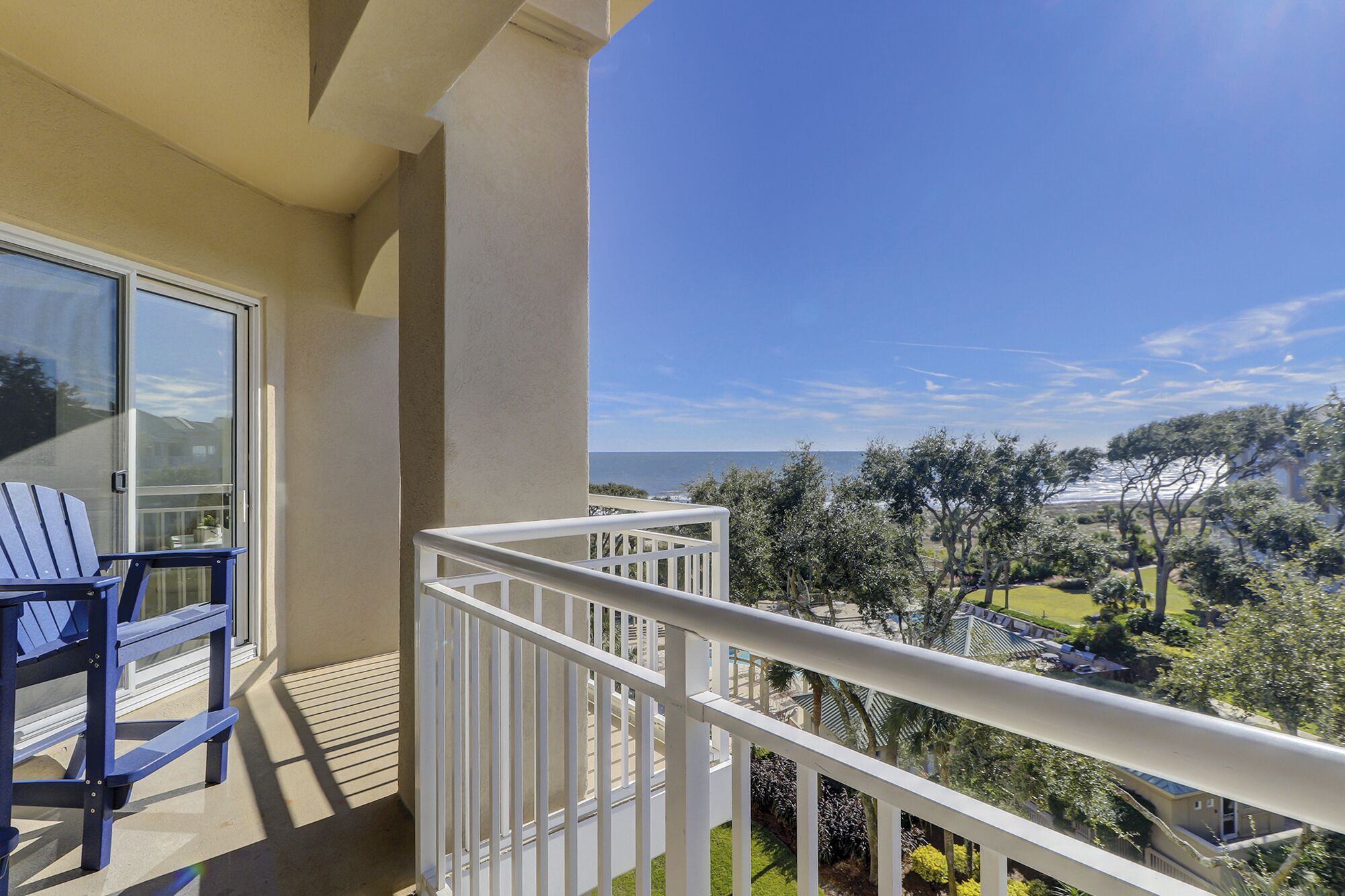A balcony with a view of the sea and surrounding greenery.
