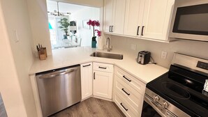 A compact kitchen with white cabinets, a stainless steel dishwasher, a black stove, and a microwave. - Beautiful Oceanview Townhouse 2 Bed 2.5 Bath SH 430 (St. Augustine)