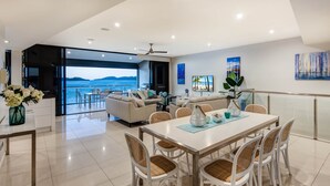A modern living room with a large glass door leading to a balcony with a view of the sea.