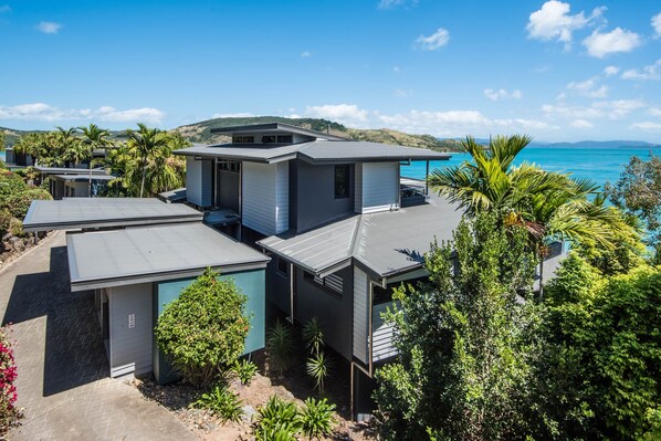 A modern coastal property with multiple units, each featuring a balcony and a view of the sea.