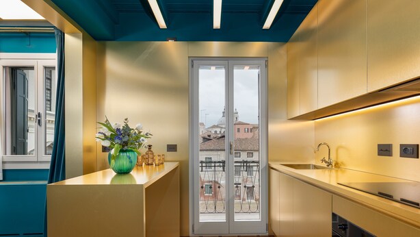 A modern kitchen with a large window, a built-in sink, and a decorative vase on the counter. - Dimora San Trovaso (Venice)
