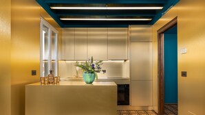 A modern kitchen with a central island, stainless steel appliances, and a blue accent wall. - Dimora San Trovaso (Venice)