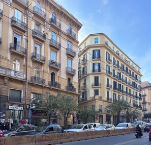 Un edificio de varios pisos con balcones, un escaparate con maniquíes y coches aparcados.