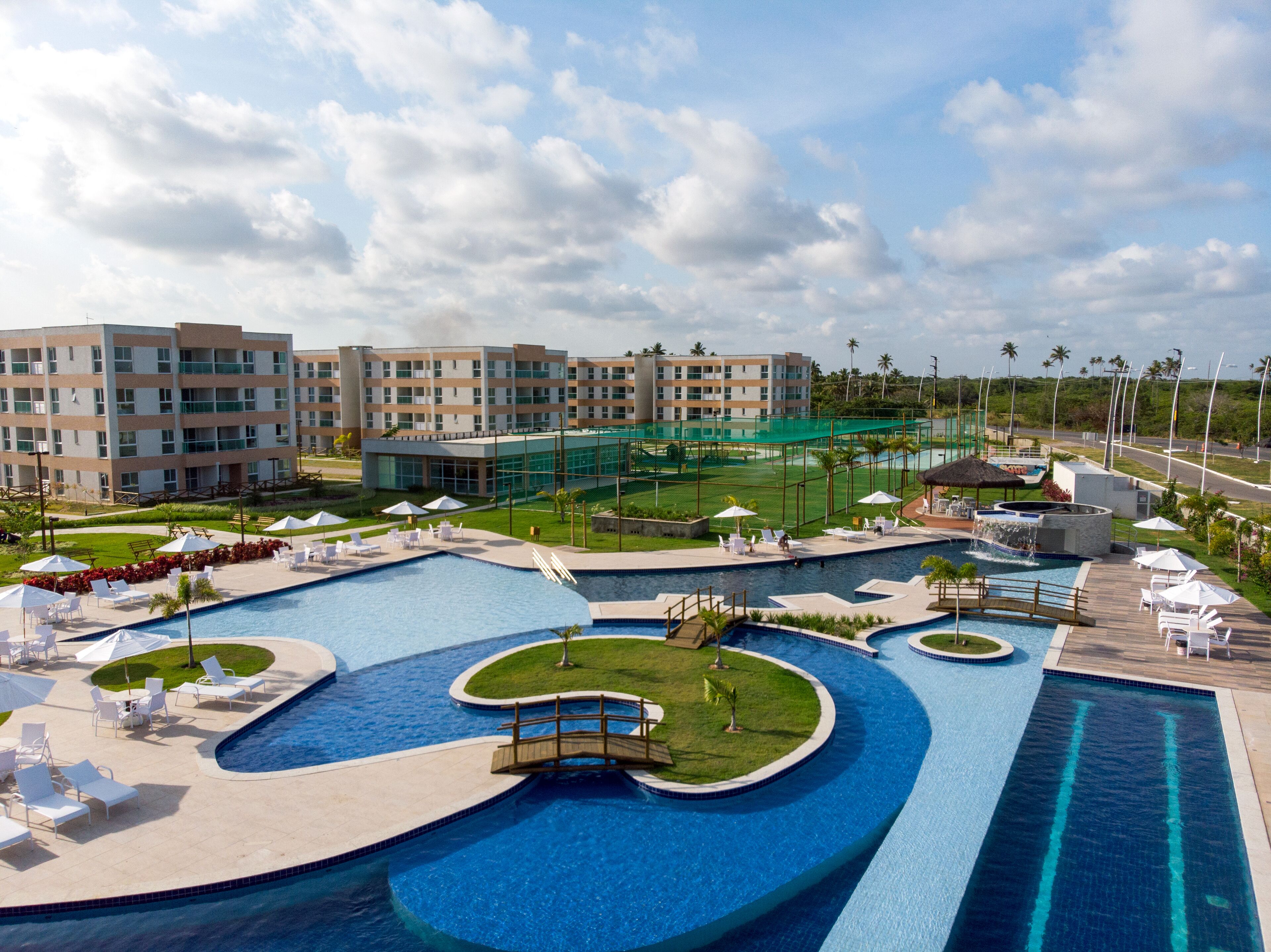 A resort with multiple swimming pools, sun loungers, and a large building with multiple floors.