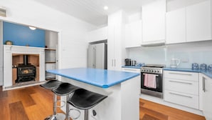 A modern kitchen with white cabinets, a blue countertop, a built-in oven, and a black stove. - Esplanade Premium 33 Steps to Beach (Torquay)