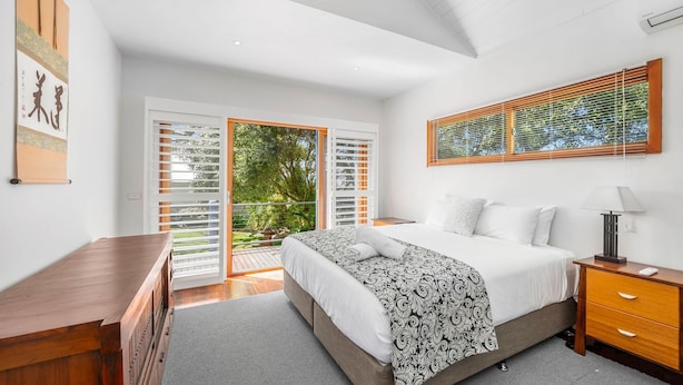 A bedroom with a bed, a nightstand, a desk, and a window with blinds. - Esplanade Premium 33 Steps to Beach (Torquay)
