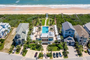 A beachfront resort with a central pool, multiple guest houses, and a beach view.