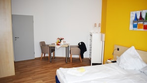 Habitació d'hotel amb llit, escriptori, cadira, armari i un quadre al mur.
