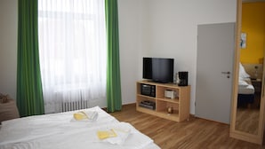 Habitació d'hotel amb llit, televisió, cafetera i un armari de fusta.