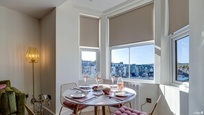 A dining area with a table set for four, large windows offering a view of the city, and a floor lamp on the left. - North Marine Villa - Apt 3 - Second floor modern apartment near North Bay Beach. (Scarborough)