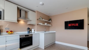 A modern kitchen with white cabinets, a built-in oven, a sink, and a wall-mounted TV displaying the Netflix logo. - North Marine Villa - Apt 3 - Second floor modern apartment near North Bay Beach. (Scarborough)