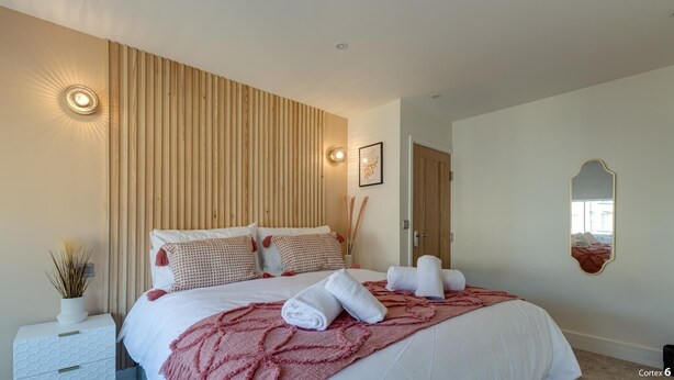 A modern bedroom with a large bed, a bedside table, a wall-mounted light, and a mirror. - North Marine Villa - Apt 3 - Second floor modern apartment near North Bay Beach. (Scarborough)