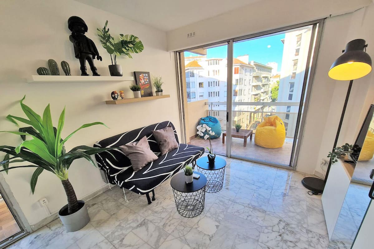 A modern living room with a sofa, coffee table, and potted plants.