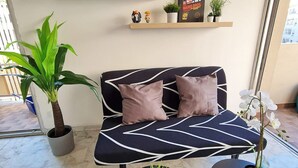 Una sala de estar moderna con un sofá, dos mesitas auxiliares y varias plantas.