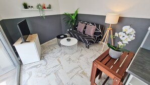 Un salón moderno con suelo de mármol, un sofá blanco y negro, una mesita redonda y una orquídea en maceta.
