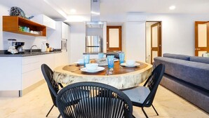 A modern kitchen with white cabinets, a built-in oven, and a dining area with a round table and black chairs. - 2BR Condo Beautiful Common Areas, Sleeps 6! (Akumal)