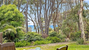 Relax on a bench amidst lush greenery with a serene ocean view.