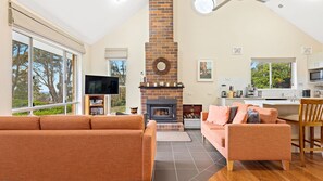 Relax in this spacious living area with a brick fireplace, large windows, and comfortable seating for two.